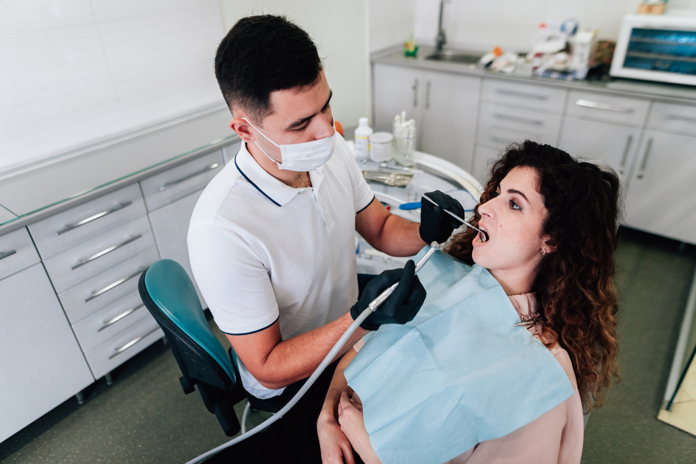 one of the best dentists in Mississauga performs a root canal treatment on his female patient.